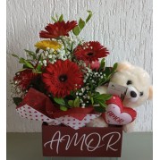 Arranjo de rosas e urso de pelúcia.